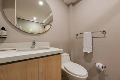 a bathroom with a white toilet and a mirror at Estelar Apartamentos Medellin in Medellín