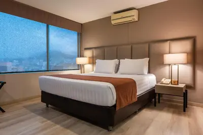 a bedroom with a large bed and a large window at Estelar Apartamentos Medellin in Medellín