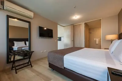 a bedroom with a large bed and a mirror at Estelar Apartamentos Medellin in Medellín