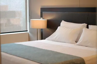 a bedroom with a bed with white pillows and a lamp at Estelar Apartamentos Medellin in Medellín