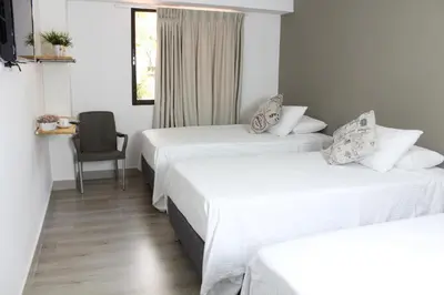 a hotel room with three beds and a chair at Hotel Boutique Plaza in Medellín