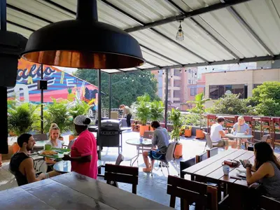 a group of people sitting at tables in a restaurant at Noah boutique hostels Medellín in Medellín