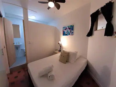 a small bedroom with a white bed and a bathroom at Noah boutique hostels Medellín in Medellín