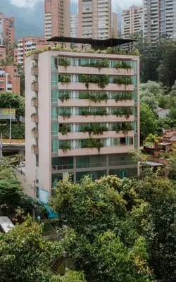 a tall white building with trees in front of it at 1616 Hotel in Medellín