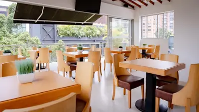 a restaurant with wooden tables and chairs and windows at Hotel Madeiro in Medellín