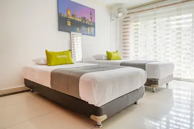 two twin beds in a room with a window at Hotel Boutique Laureles Home - Ayenda 1258 in Medellín
