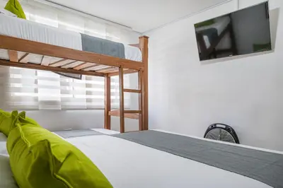 a bedroom with two bunk beds and a flat screen tv at Hotel Boutique Laureles Home - Ayenda 1258 in Medellín