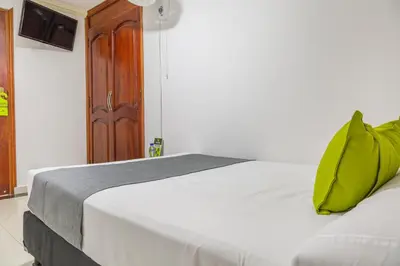 a white bed with a green pillow on top of it at Hotel Boutique Laureles Home - Ayenda 1258 in Medellín