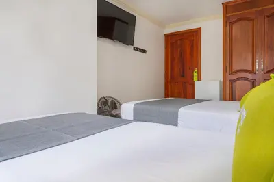 a bedroom with two beds and a tv on the wall at Hotel Boutique Laureles Home - Ayenda 1258 in Medellín