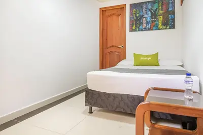 a small bedroom with a bed and a table at Hotel Boutique Laureles Home - Ayenda 1258 in Medellín