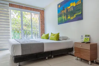 a bedroom with a bed with green pillows and a window at Hotel Boutique Laureles Home - Ayenda 1258 in Medellín