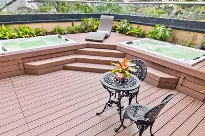 a deck with a hot tub and a table and chairs at GHL Hotel Portón Medellín in Medellín