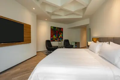a hotel room with a large bed and a flat screen tv at GHL Hotel Portón Medellín in Medellín
