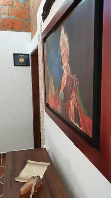 a painting hanging on a wall with a wooden table at El Quijote Apartahotel in Jericó