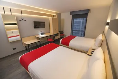 a hotel room with two beds and a desk at City Express Plus by Marriott Medellín Colombia in Medellín