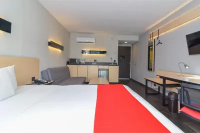 a hotel room with a large bed and a kitchen at City Express Plus by Marriott Medellín Colombia in Medellín