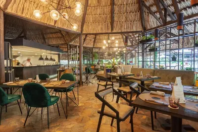 a restaurant with wooden tables and green chairs at InterContinental Medellin - Movich by IHG in Medellín