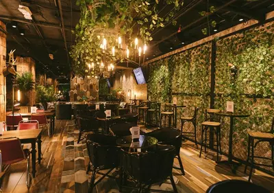 a restaurant with tables and chairs and plants on the walls at InterContinental Medellin - Movich by IHG in Medellín