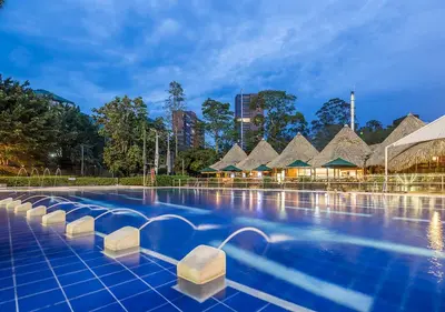 a pool at a resort with thatched roofs at InterContinental Medellin - Movich by IHG in Medellín