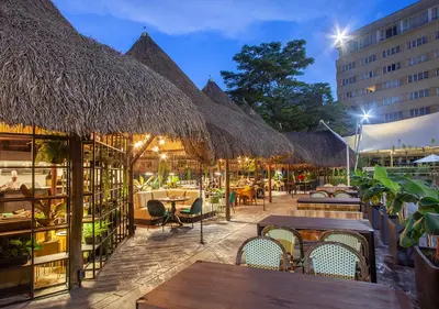 a restaurant with tables and chairs and straw umbrellas at InterContinental Medellin - Movich by IHG in Medellín