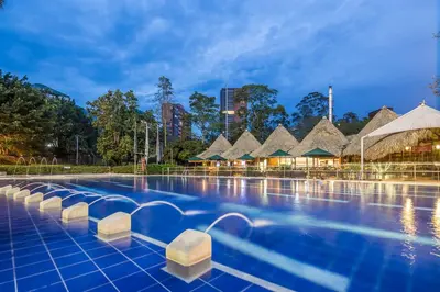 a pool at a resort with thatched roofs at InterContinental Medellin - Movich by IHG in Medellín