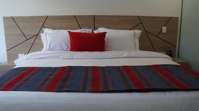 a bed with two pillows and a red pillow on it at Obo Hotel in Medellín