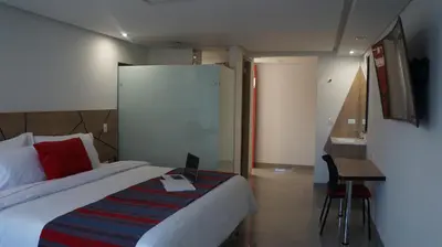 a bedroom with a bed and a desk with a laptop at Obo Hotel in Medellín