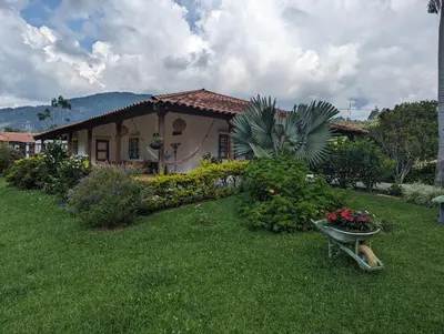 a house with a wheelbarrow of flowers in a yard at Patio Bonito in Jardin
