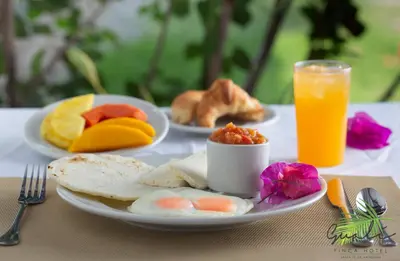 a table with plates of food and a glass of orange juice at Finca Hotel Guali Santafe in Santa Fe de Antioquia
