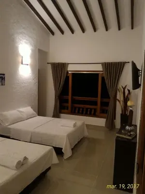 a hotel room with two beds and a window at Finca Hotel Guali Santafe in Santa Fe de Antioquia