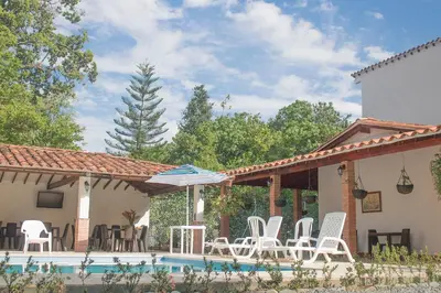 a patio with white chairs and a swimming pool at Finca Hotel Guali Santafe in Santa Fe de Antioquia