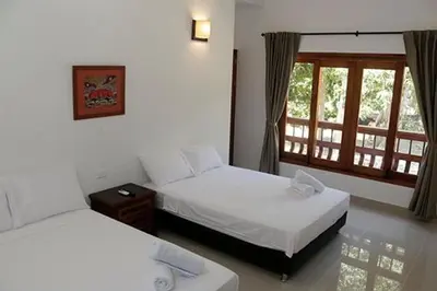 a hotel room with two beds and a window at Finca Hotel Guali Santafe in Santa Fe de Antioquia
