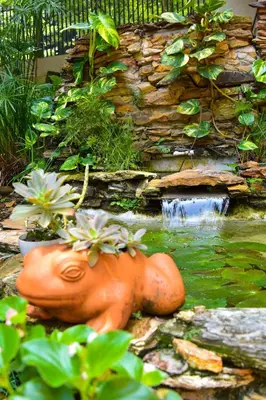 a statue of a jug in a pond with a waterfall at La Campana Hotel Boutique in Medellín