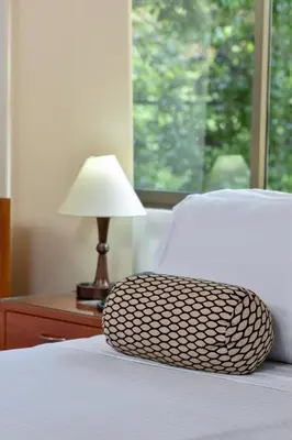 a bed with a pillow on it with a lamp and a window at La Campana Hotel Boutique in Medellín