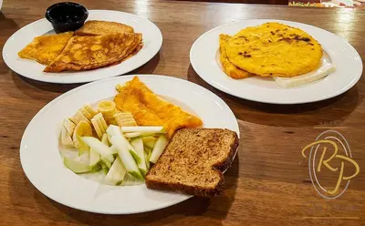 three plates of food on a wooden table at Hotel Rio Piedras in Jericó