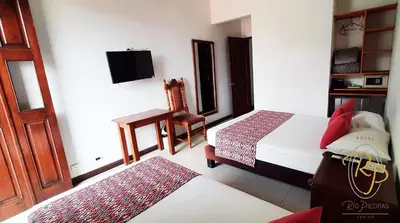 a bedroom with a bed and a chair and a television at Hotel Rio Piedras in Jericó
