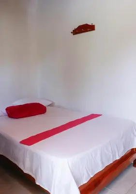a white bed with a red pillow on top of it at Hotel La Casona - San Luis in San Luis