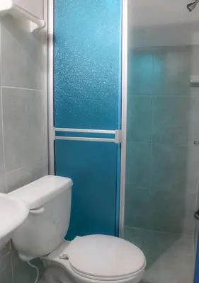 a bathroom with a toilet and a blue shower door at Hotel La Casona - San Luis in San Luis