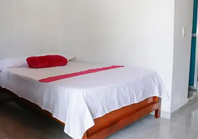a bed with a red pillow on top of it at Hotel La Casona - San Luis in San Luis