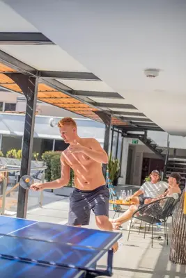 a shirtless young man playing a game on a table at Medellín Vibes in Medellín