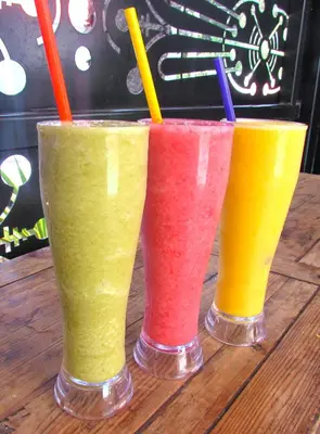 three different colored drinks sitting on a wooden table at Medellín Vibes in Medellín