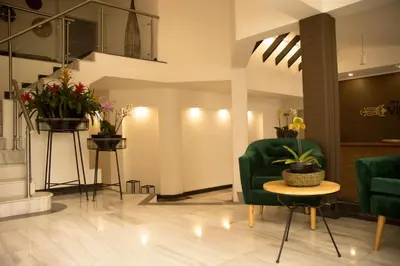 a lobby with green chairs and a table and flowers at Medellín Vibes in Medellín