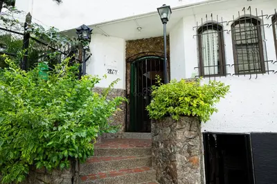 a white house with a black door and some bushes at Ayenda Habana Vieja 1221 in Medellín