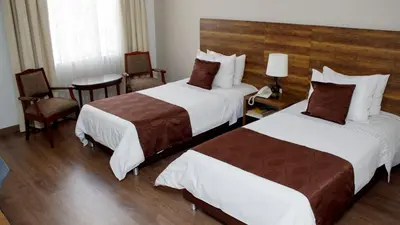a hotel room with two beds and a table and chairs at Hotel Nutibara in Medellín
