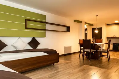 a bedroom with a bed and a dining room at Hotel Carretero in Manizales