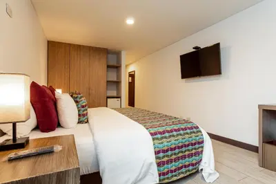 a hotel room with a bed and a flat screen tv at Hotel Carretero in Manizales