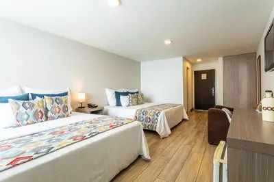 a hotel room with two beds and a desk at Hotel Carretero in Manizales