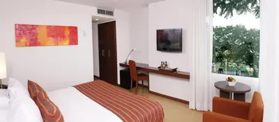 a bedroom with a bed and a desk and a television at Hotel Estelar El Cable in Manizales
