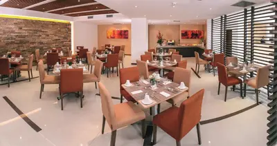 a restaurant with tables and chairs and a brick wall at Hotel Estelar El Cable in Manizales