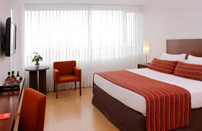 a hotel room with a bed and a chair at Hotel Estelar El Cable in Manizales